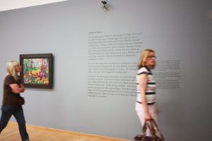 Museumsgestaltung. Besucherinnen betrachten einen Ausstellungsraum mit einer Grafik an der Wand.