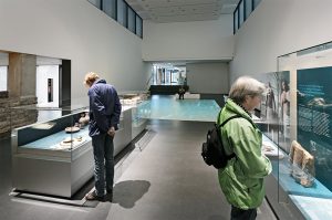 Museumsplanung. Besucher vor Glasvitrinen.