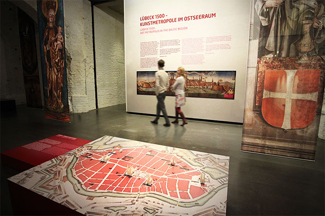 Museumsdesign. Besucher vor Ausstellungswand mit Bild und Text.